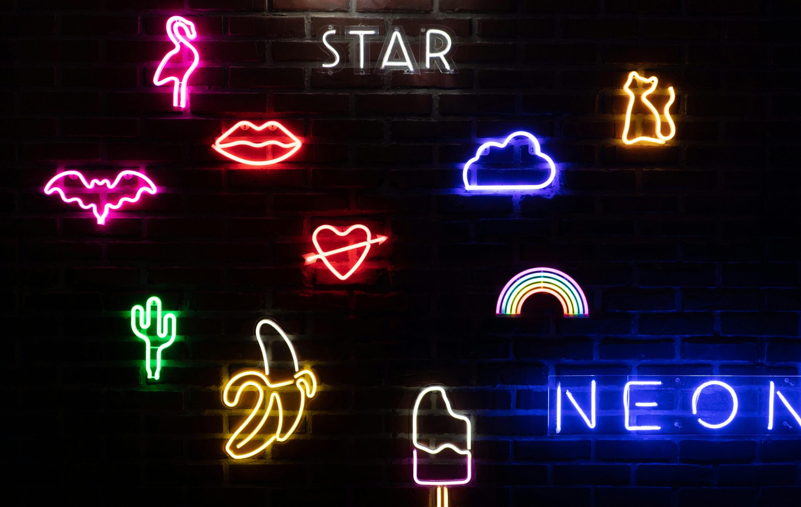 Colorful neon light art featuring diverse shapes and symbols on a brick wall.