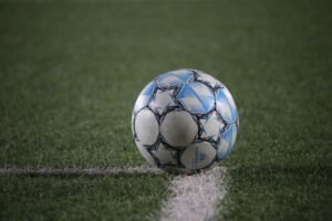 A close-up view of a soccer ball on a green field, highlighting sports theme.