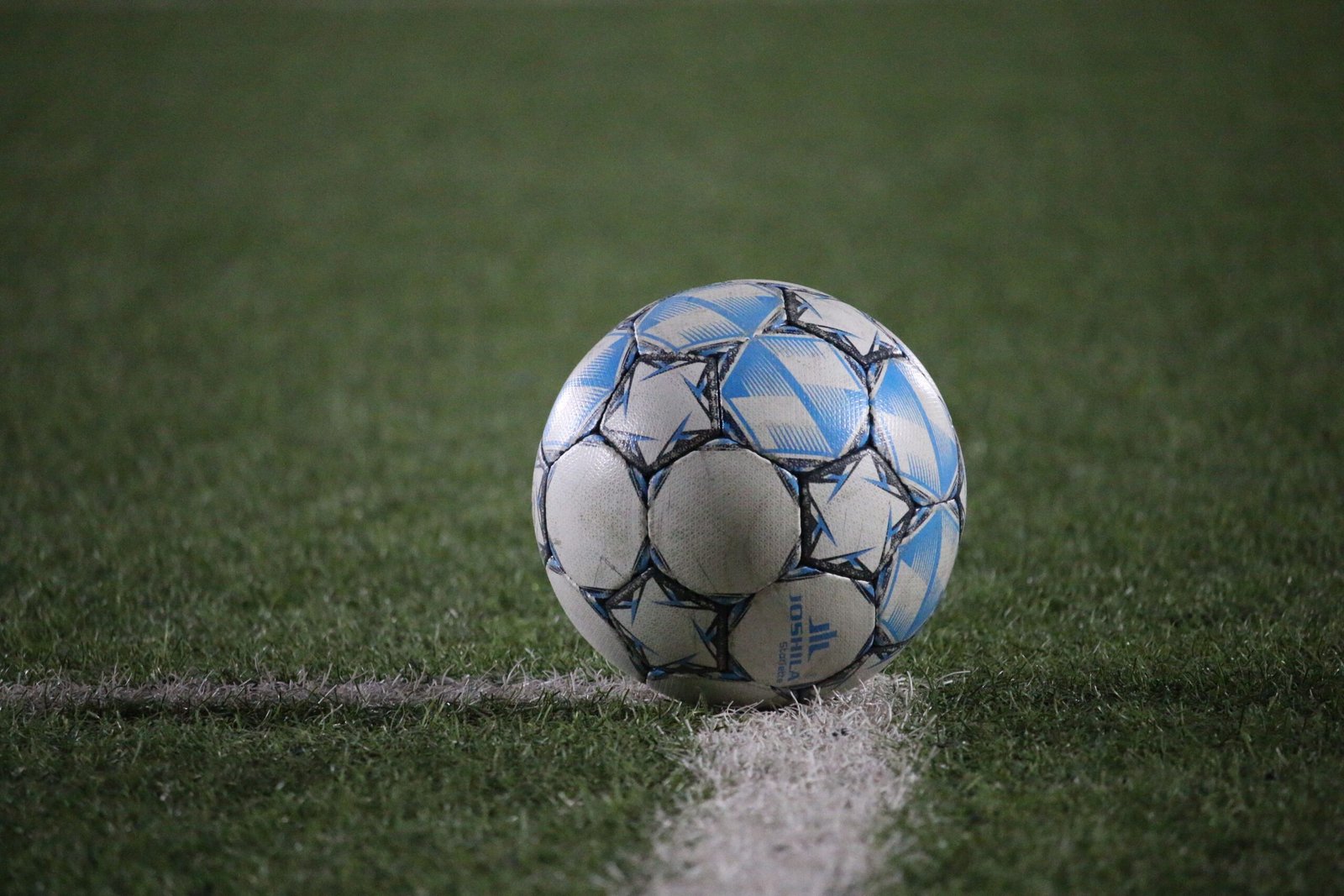 A close-up view of a soccer ball on a green field, highlighting sports theme.